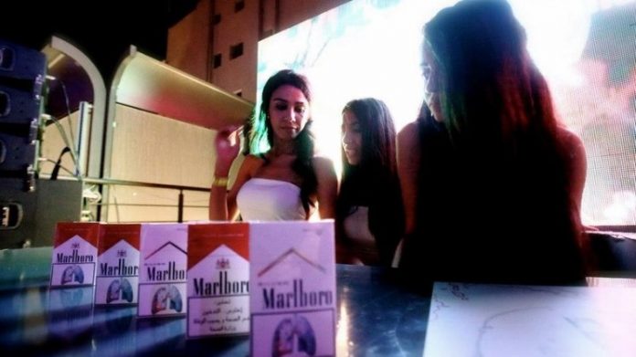 Young girls pose with boxes of Marlboro cigarettes.